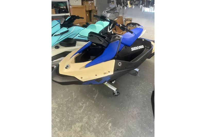 Slide: The Image of 2025 Sea-Doo Spark Trixx for 3 in showroom, blue and beige design. - 1