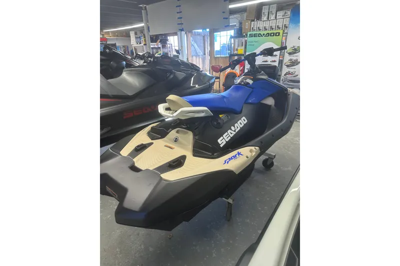 Slide: The Image of 2025 Sea-Doo Spark Trixx for 3, blue and beige, displayed in showroom. - 3