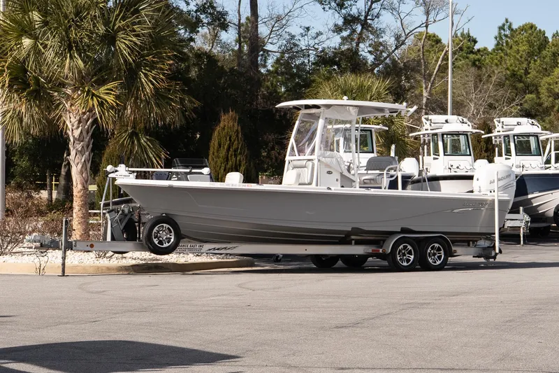 Slide: The Image of 2020 Blue Wave 2600 PureBay boat on trailer, parked near palm trees. - 2