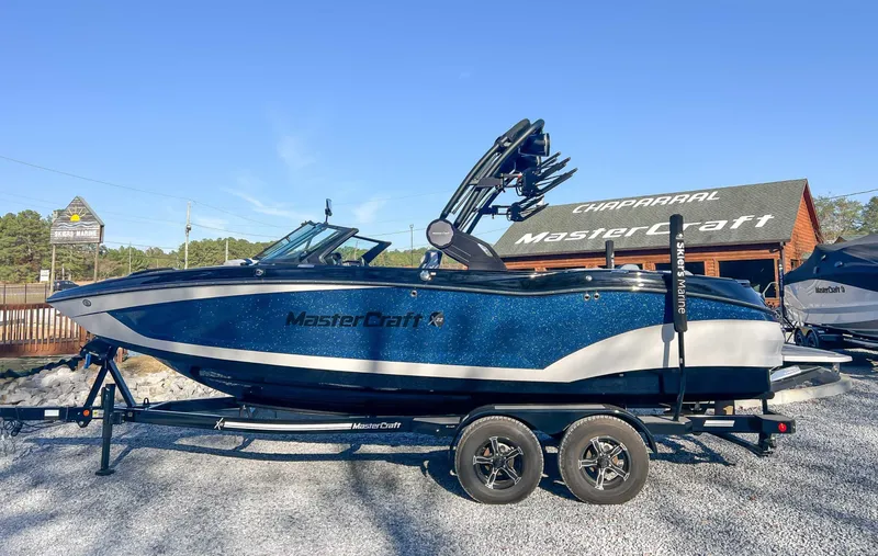The Image of 2024 MasterCraft X22 boat on trailer in front of store. - 1