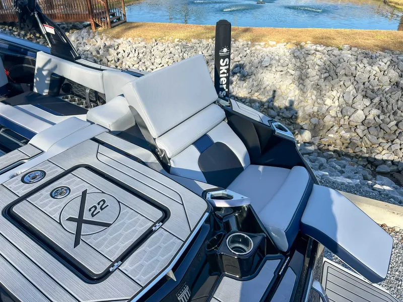 Slide: The Image of 2024 MasterCraft X22 boat with luxurious seating area by the water. - 13