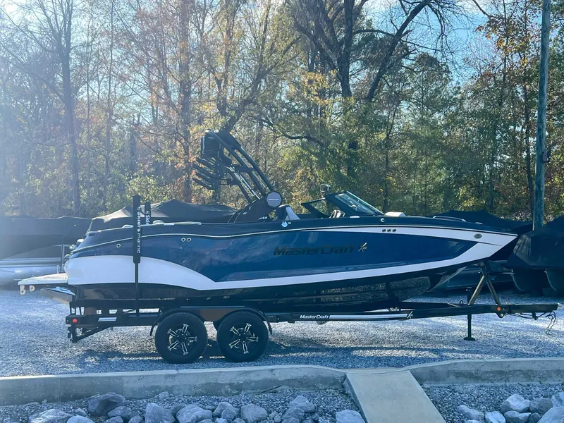 Slide: The Image of 2024 MasterCraft X22 boat on trailer outdoors. - 6