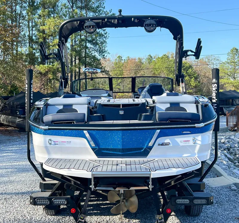 Slide: The Image of 2024 MasterCraft X22 boat, rear view, parked on gravel. - 9