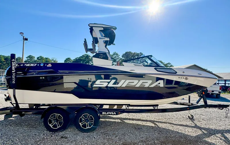 Slide: The Image of 2023 Supra SL boat on trailer under bright sun. - 6