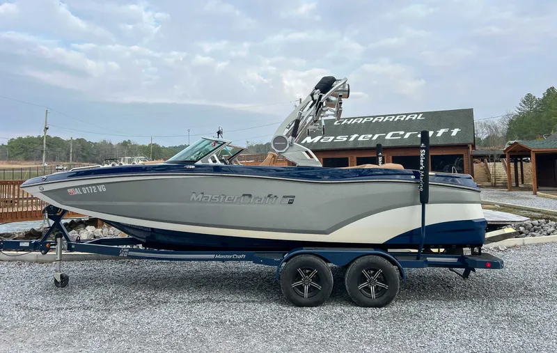 The Image of 2021 MasterCraft XT22 boat on trailer in front of building. - 1