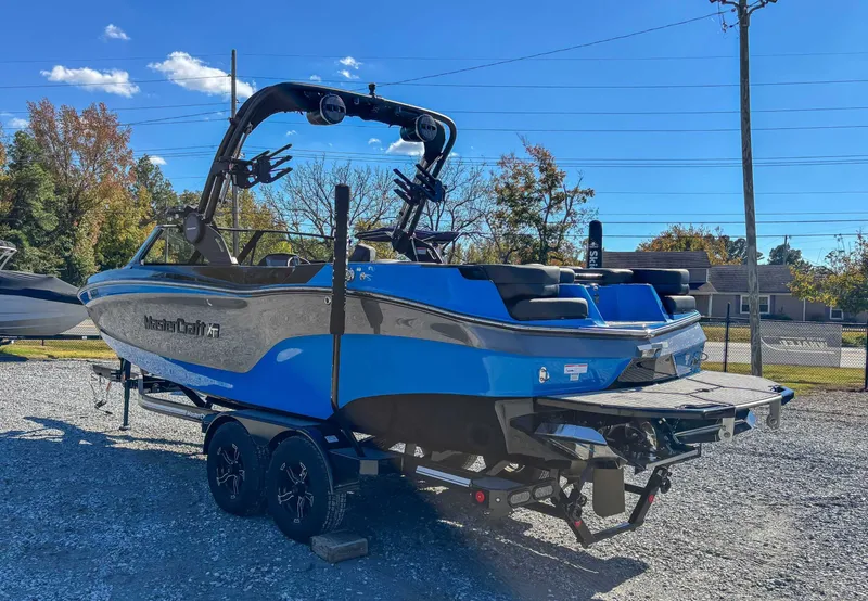 Slide: The Image of 2024 MasterCraft XT24 boat on trailer, blue hull, sunny day. - 7