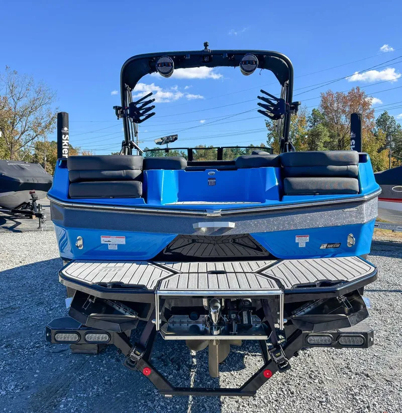 Slide: The Image of Rear view of blue 2024 MasterCraft XT24 boat on gravel. - 9