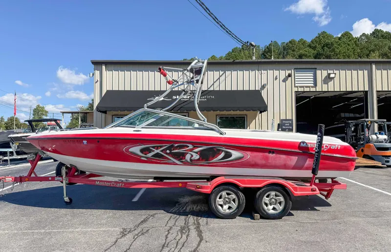 The Image of Red 2002 MasterCraft X30 boat on trailer in front of warehouse. - 1