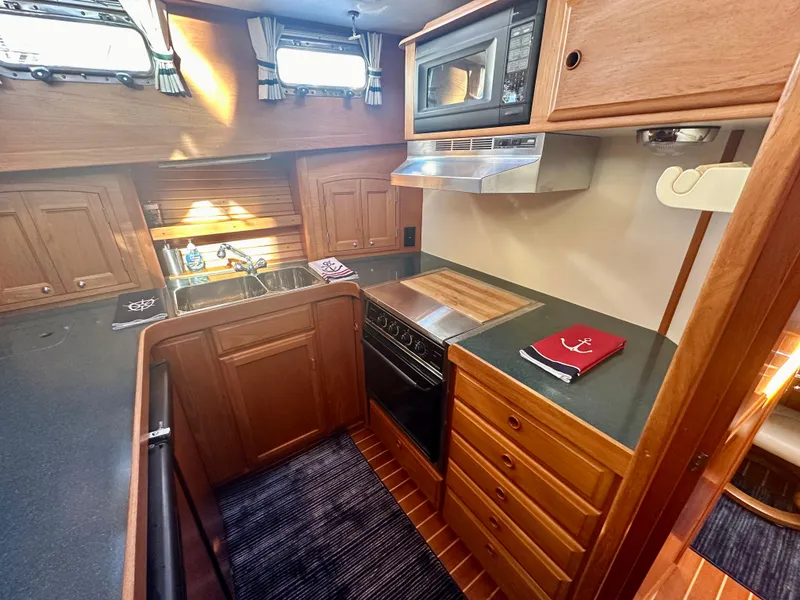 Slide: The Image of 1997 Sabre Cockpit Motor Yacht kitchen with wood cabinetry, stove, and microwave. - 22