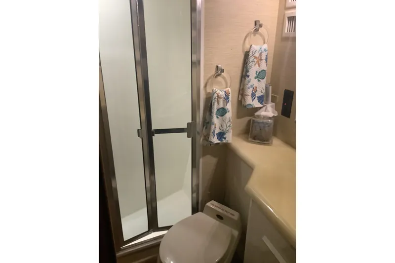 Slide: The Image of Bathroom in 1994 Viking 50' Convertible Sportfish with shower, toilet, and nautical-themed towels. - 28