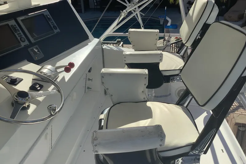 Slide: The Image of 1994 Viking 50' Convertible Sportfish helm with steering wheel and cushioned seats. - 5