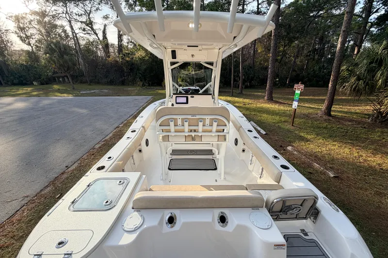 Slide: The Image of 2022 Sea Fox 228 Commander boat interior with seating and console, parked near trees. - 91