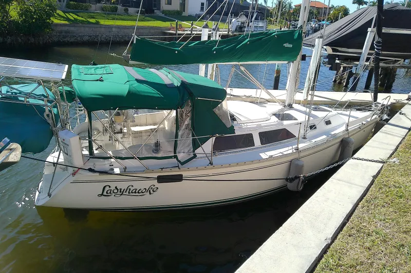 The Image of 1991 Hunter 30 sailboat docked, featuring green covers and solar panels. - 1