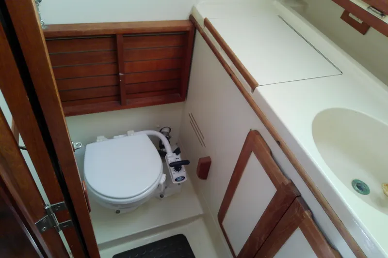 Slide: The Image of 1991 Hunter 30 sailboat bathroom with toilet, sink, and wooden cabinetry. - 36