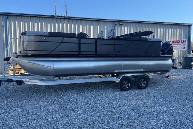 The Image of 2026 Veranda Relax VR 22 RC pontoon boat on trailer, parked on gravel. - 1