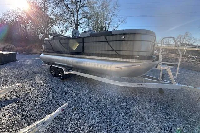 Slide: The Image of 2026 Veranda Relax VR 22 RC pontoon boat on trailer, parked on gravel. - 3