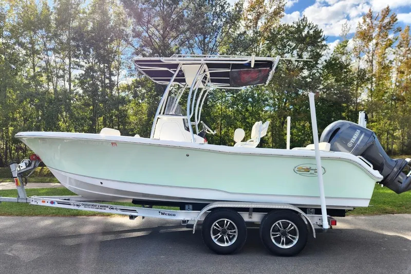 The Image of 2023 Sea Hunt Ultra 219 boat on trailer, parked outdoors with trees in background. - 0