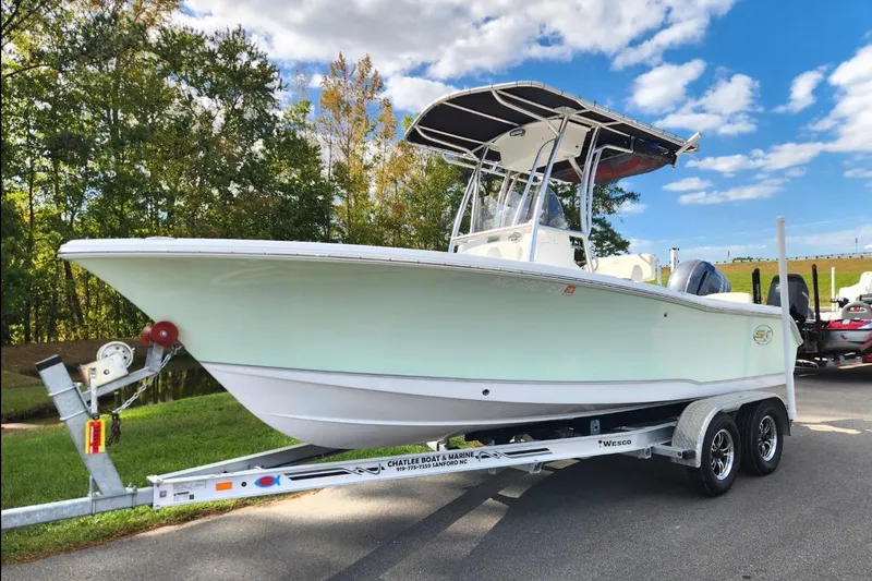 Slide: The Image of 2023 Sea Hunt Ultra 219 boat on trailer, parked outdoors under blue sky. - 1