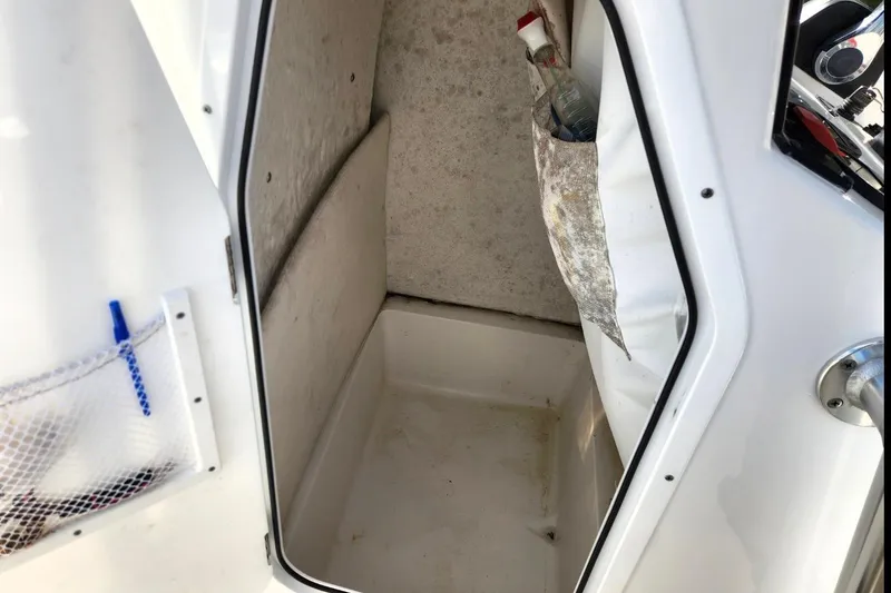Slide: The Image of 2023 Sea Hunt Ultra 219 storage compartment with open door and interior view. - 16