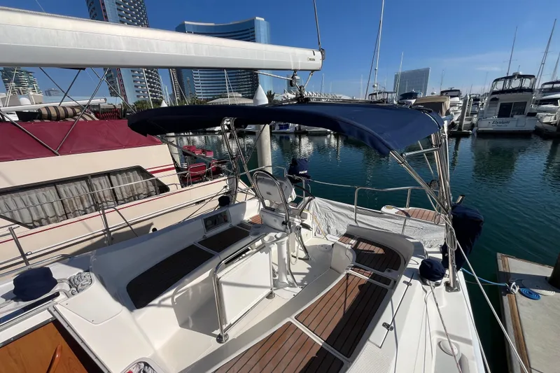 Slide: The Image of 2008 Hunter 36 sailboat docked in marina, featuring spacious deck and blue canopy. - 6