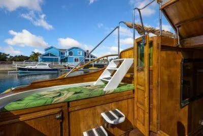 Slide: The Image of 1950 Monk Pilothouse boat with wooden deck, docked near blue houses under a clear sky. - 11