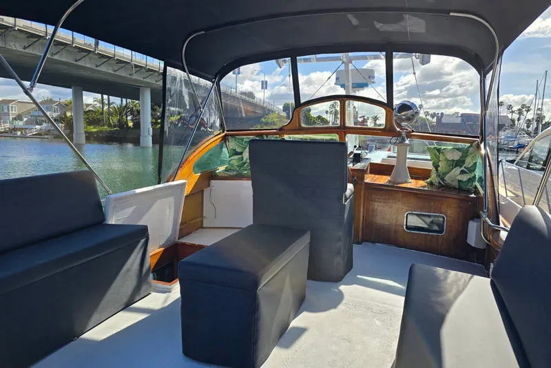 Slide: The Image of 1950 Monk Pilothouse interior with seating, under a bridge, sunny day. - 18