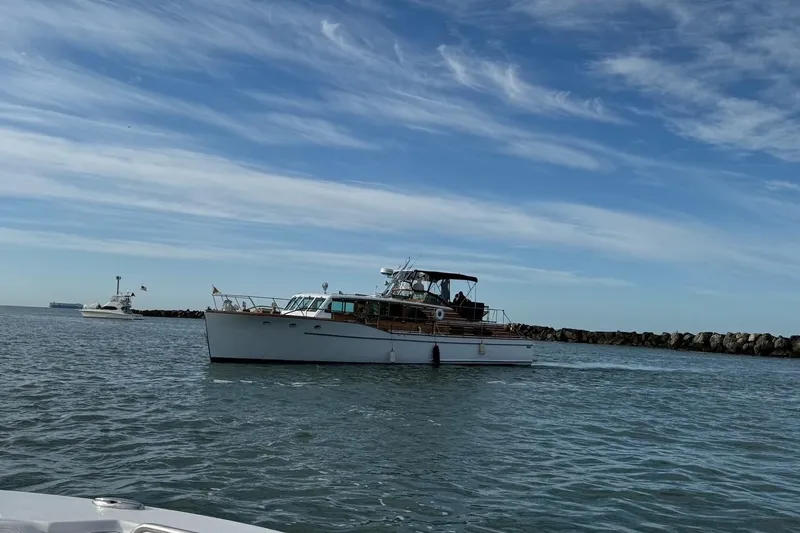 Slide: The Image of 1950 Monk Pilothouse boat on calm water under a clear blue sky. - 2