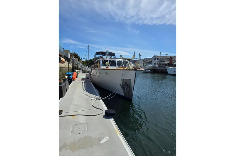 Slide: The Image of 1950 Monk Pilothouse boat docked at a marina under a clear blue sky. - 3