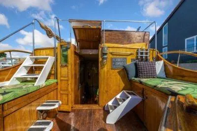 Slide: The Image of 1950 Monk Pilothouse boat with wooden deck and green cushions under blue sky. - 8