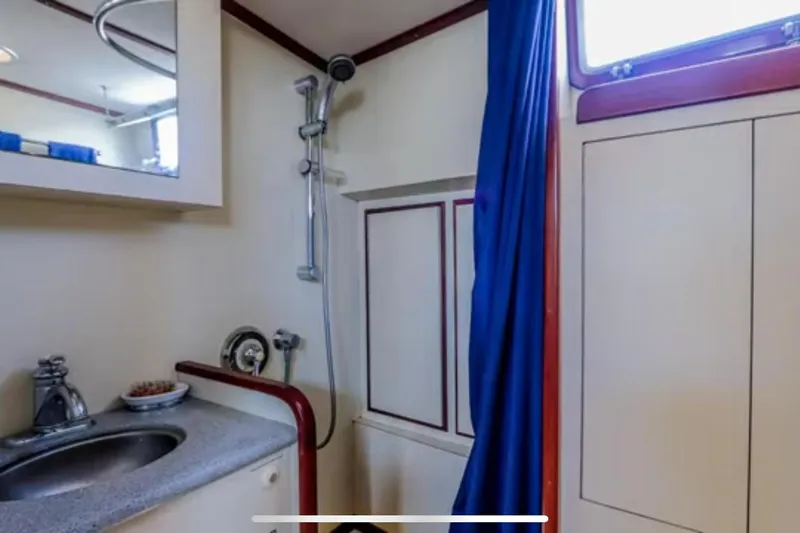 Slide: The Image of 1969 Islander 72 Aft Cabin Motor Yacht bathroom with shower, sink, and blue curtain. - 15