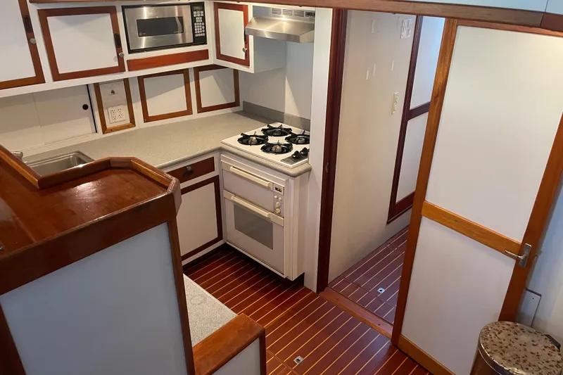 Slide: The Image of 1969 Islander 72 Aft Cabin Motor Yacht kitchen with stove, microwave, and wood accents. - 9
