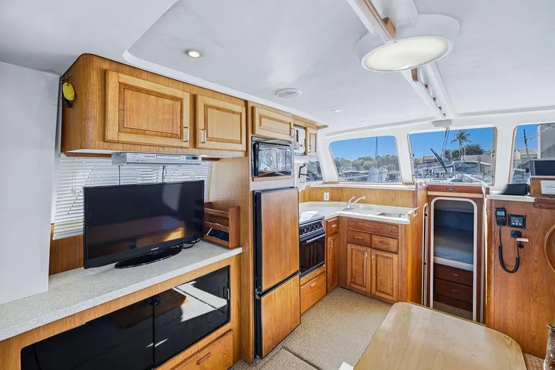Slide: The Image of Interior of 1998 Mainship 350 Trawler with kitchen, TV, and wooden cabinetry. - 11