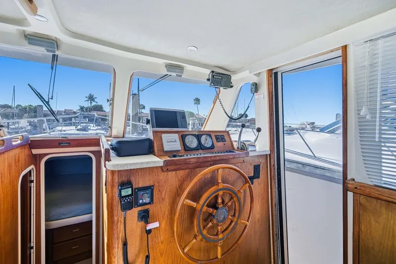 Slide: The Image of 1998 Mainship 350 Trawler helm with wooden wheel, navigation equipment, and cabin view. - 13
