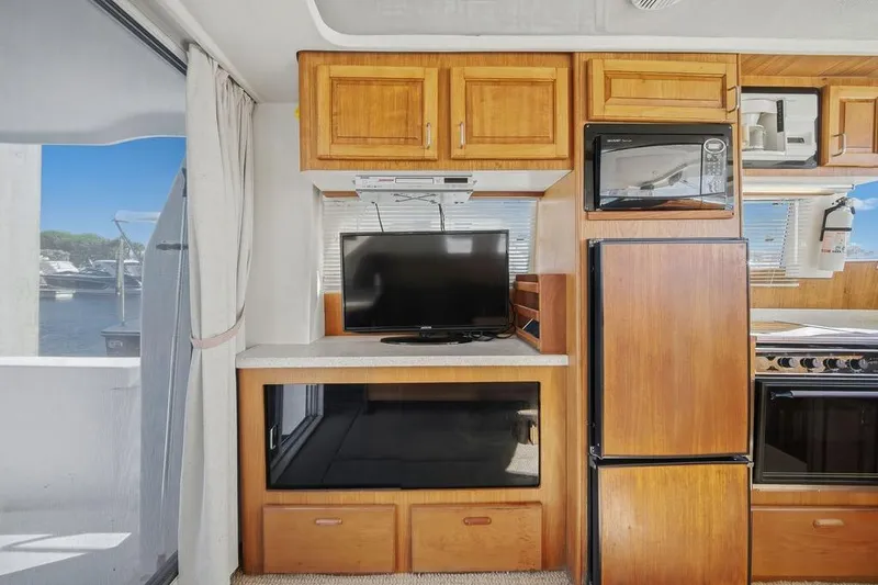 Slide: The Image of Interior of 1998 Mainship 350 Trawler with TV, microwave, and wooden cabinetry. - 15
