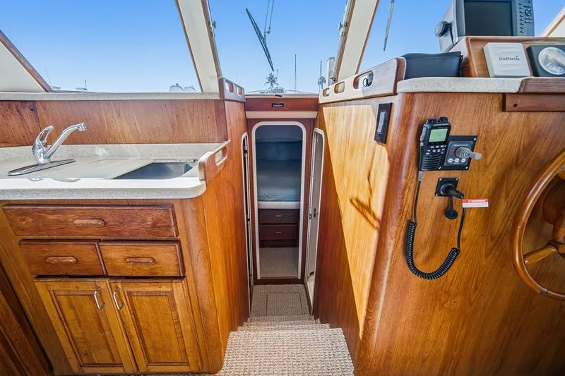 Slide: The Image of 1998 Mainship 350 Trawler interior with wooden cabinetry, sink, and navigation equipment. - 17