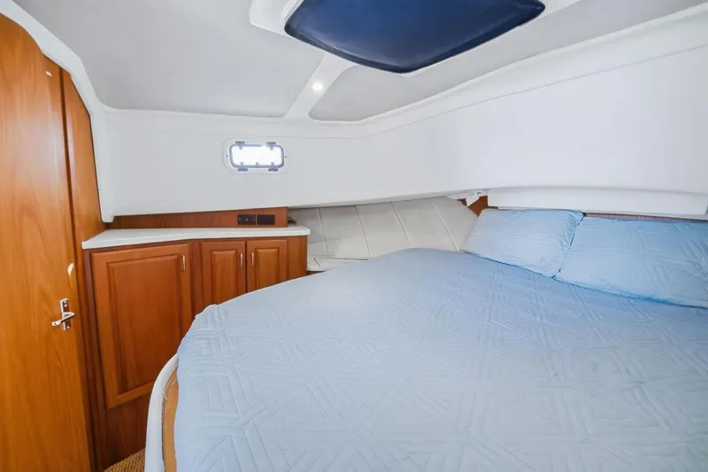 Slide: The Image of Cozy cabin interior of 1998 Mainship 350 Trawler with blue bedding and wooden cabinetry. - 19