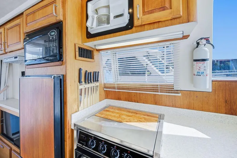Slide: The Image of 1998 Mainship 350 Trawler kitchen with microwave, stove, knife set, and fire extinguisher. - 23