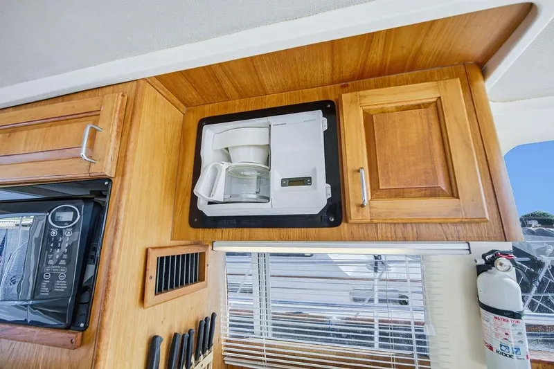 Slide: The Image of 1998 Mainship 350 Trawler interior with built-in coffee maker and wooden cabinetry. - 24