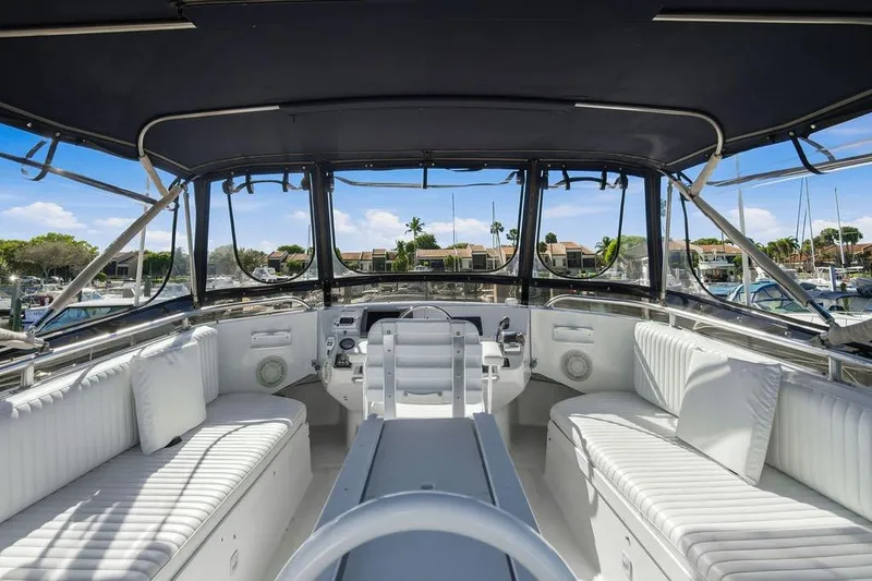Slide: The Image of 1998 Mainship 350 Trawler interior with white seating, helm, and marina view. - 26