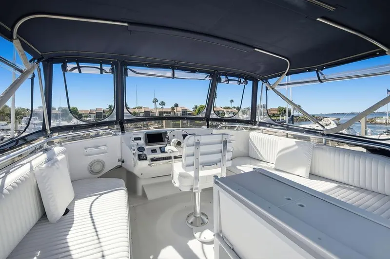 Slide: The Image of 1998 Mainship 350 Trawler interior with white seating and helm, docked at marina. - 27