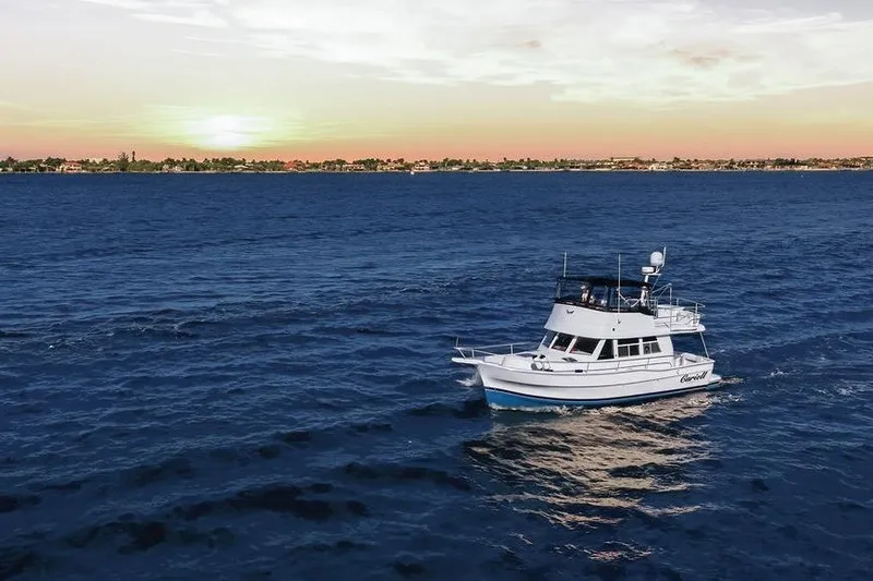 Slide: The Image of 1998 Mainship 350 Trawler cruising on ocean at sunset, scenic coastal view. - 29