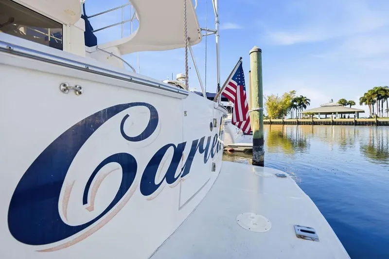 Slide: The Image of 1998 Mainship 350 Trawler docked, featuring American flag and scenic waterfront view. - 6