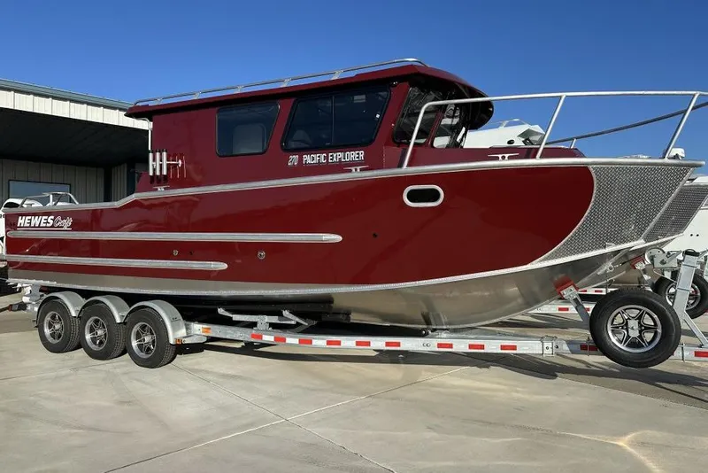 The Image of 2026 Hewescraft 270 Pacific Explorer boat on trailer, red exterior, parked outdoors. - 1