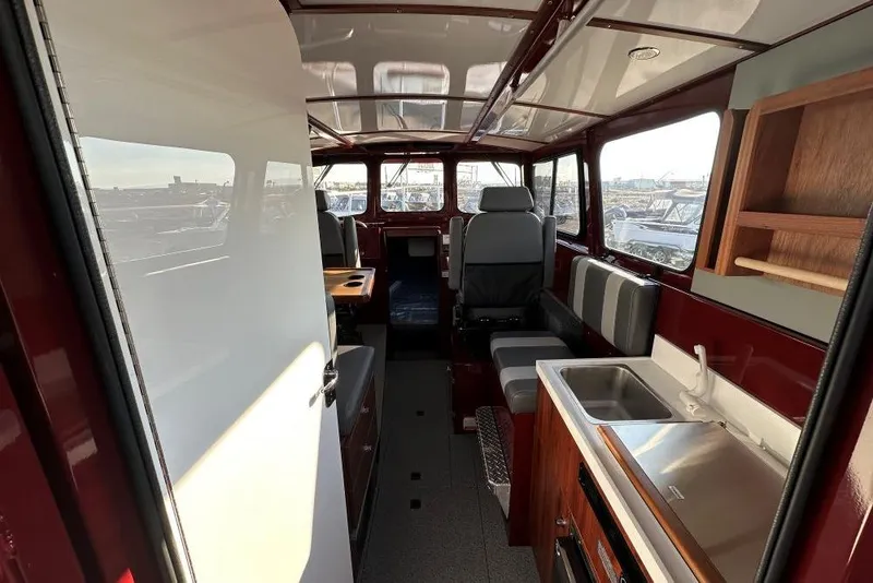 Slide: The Image of Interior of 2026 Hewescraft 270 Pacific Explorer, featuring seating, sink, and wooden cabinetry. - 5
