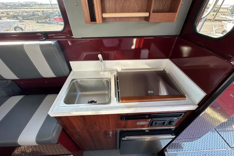 Slide: The Image of 2026 Hewescraft 270 Pacific Explorer interior with sink, stove, and seating. - 6