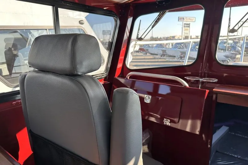 Slide: The Image of Interior of 2026 Hewescraft 270 Pacific Explorer boat, featuring a comfortable seat and window view. - 9