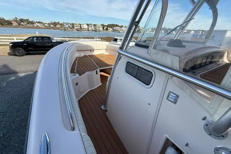 Slide: The Image of 2007 Grady-White Bimini 306 boat with wooden deck, docked near waterfront homes. - 26