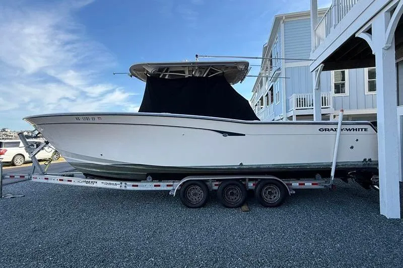 Slide: The Image of 2007 Grady-White Bimini 306 boat on trailer, parked near coastal homes. - 5