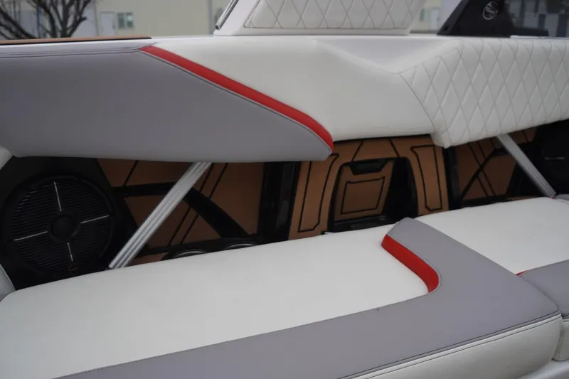 Slide: The Image of 2022 Tigé 22RZX boat interior with white and red upholstery, featuring speaker and storage area. - 51