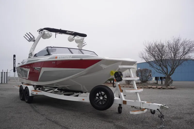 Slide: The Image of 2022 Tigé 22RZX boat on trailer, red and white design, parked outdoors. - 6